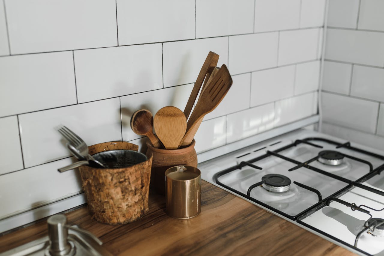 who-we-are A stylish kitchen counter featuring wooden utensils and a gas stove.