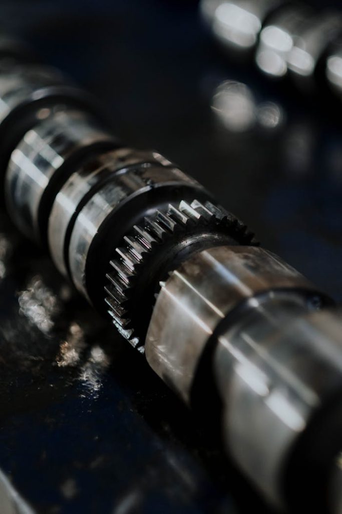 Detailed image of a camshaft showcasing gears and reflections on a dark surface.